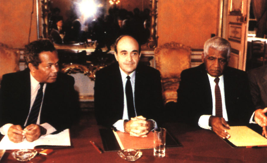Jean-Marie Tjibaou (droite) et Jacuqes Lafleur (centre) se tiennent en face de Michel Rocard, alors Prémier ministre, lors de la signature des Accords de Matignon. Première étape d'un long processus de décolonisation ©DR 
