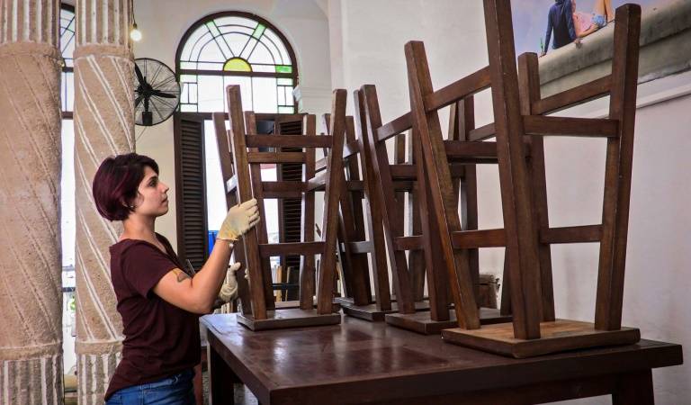 Loliet Gonzalez range des tabourets dans El Café, cafétéria de La Havane fermée pour cause d'épidémie de coronavirus, le 16 avril 2020 ©Adalberto Roque / AFP